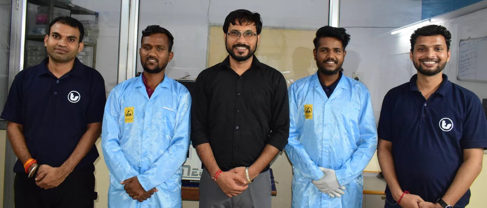 Five Techshlok team members in the lab, three wearing ESD-safe coats